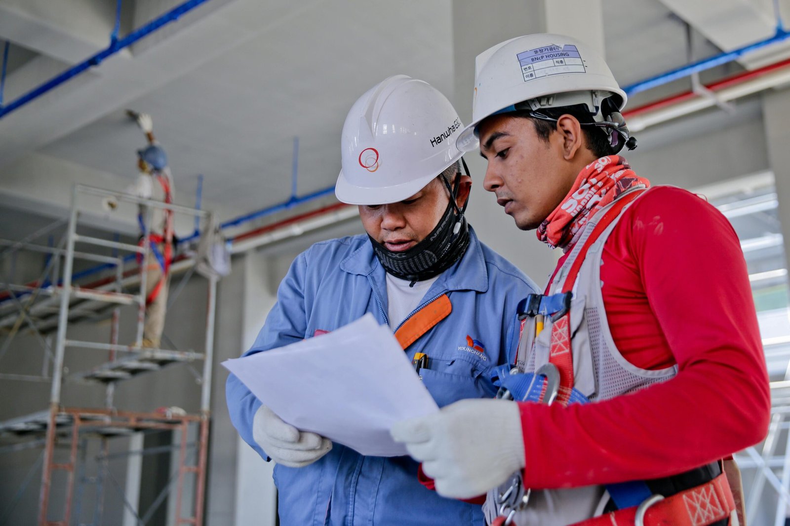 pexels-photo-1216589-1216589 Two engineers in safety helmets reviewing construction plans at a worksite.